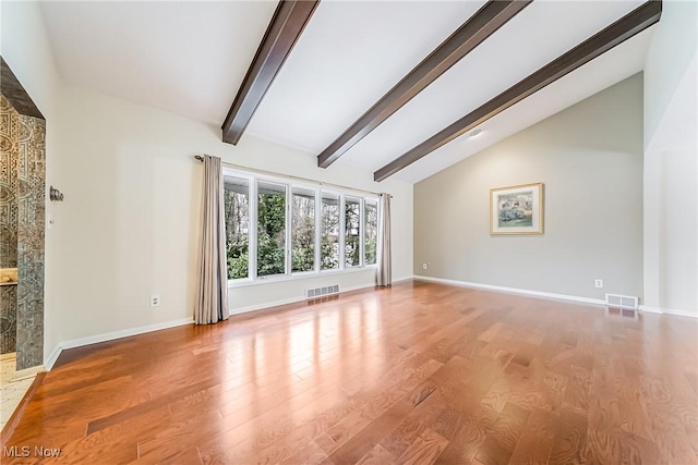 unfurnished living room featuring visible vents, beam ceiling, baseboards, and wood finished floors