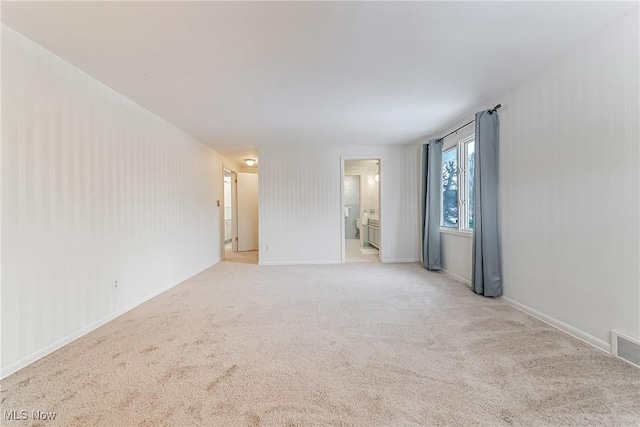 empty room featuring light colored carpet, visible vents, and baseboards