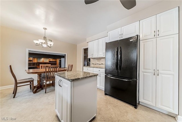 kitchen featuring dark stone countertops, white cabinetry, a center island, and freestanding refrigerator