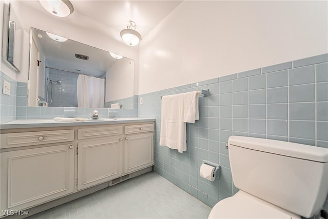 full bath featuring tile patterned floors, a shower with curtain, toilet, tile walls, and vanity