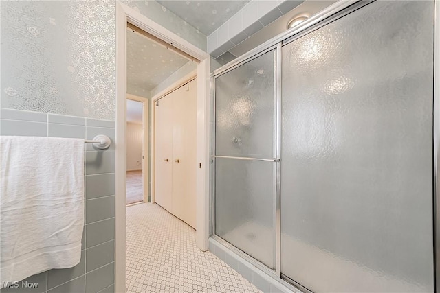 full bath with tile patterned flooring, a shower stall, and tile walls