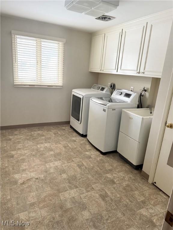 clothes washing area featuring baseboards, cabinet space, and washer and clothes dryer