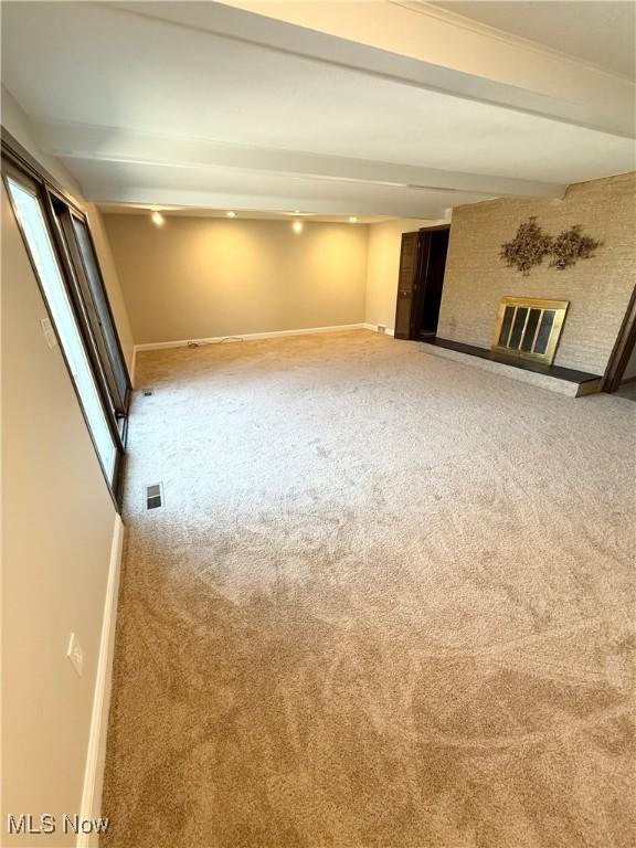 interior space featuring visible vents, a brick fireplace, baseboards, and carpet