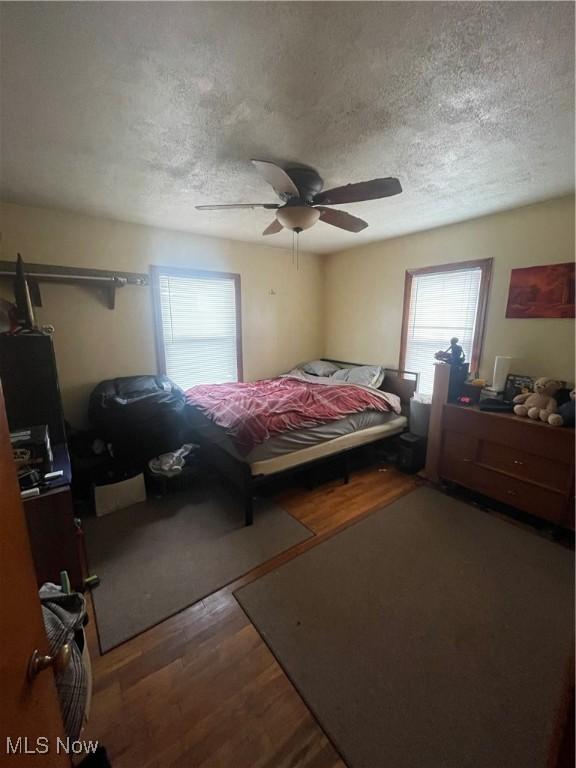 bedroom featuring hardwood / wood-style floors, a textured ceiling, and ceiling fan