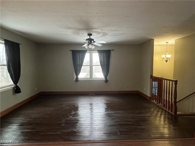 unfurnished room featuring ceiling fan with notable chandelier and dark hardwood / wood-style flooring