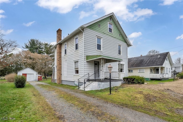 view of property featuring an outbuilding, a garage, and a front lawn