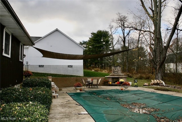 view of swimming pool with an outdoor stone fireplace and a patio area