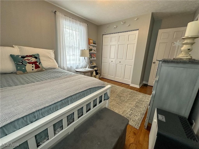 bedroom with a textured ceiling, dark hardwood / wood-style floors, and a closet