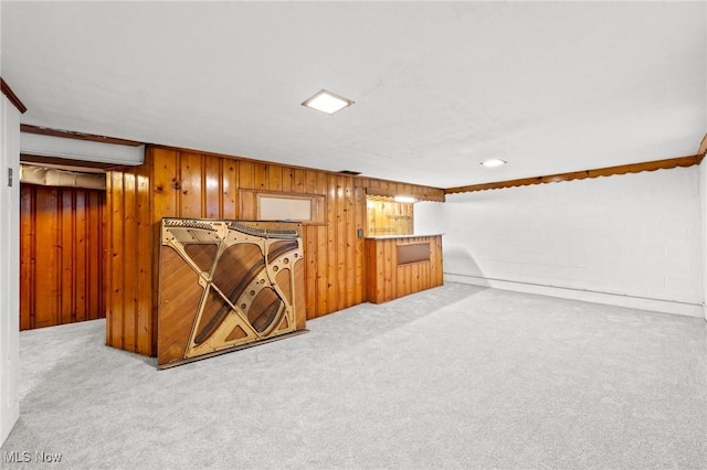 basement featuring light colored carpet and wooden walls