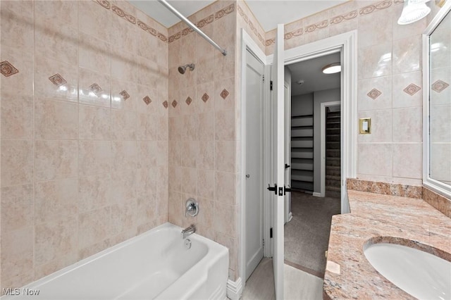 bathroom featuring tile walls, vanity, and tiled shower / bath combo