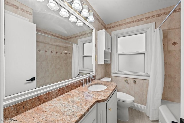 full bathroom featuring shower / bathtub combination with curtain, vanity, tile walls, and toilet