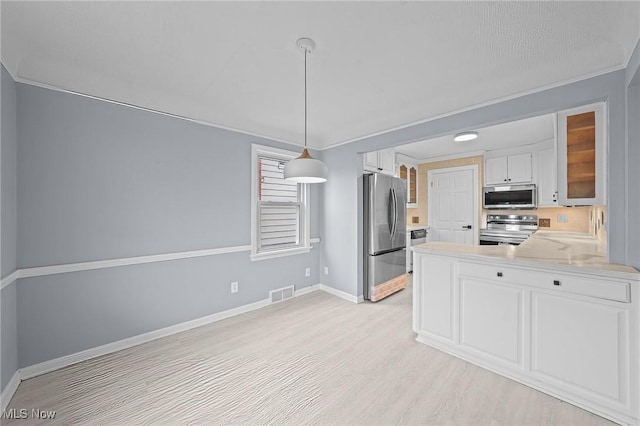 kitchen featuring white cabinetry, stainless steel appliances, kitchen peninsula, pendant lighting, and light hardwood / wood-style floors