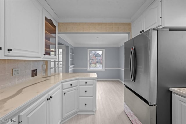 kitchen with white cabinetry, stainless steel fridge, hanging light fixtures, and light hardwood / wood-style floors