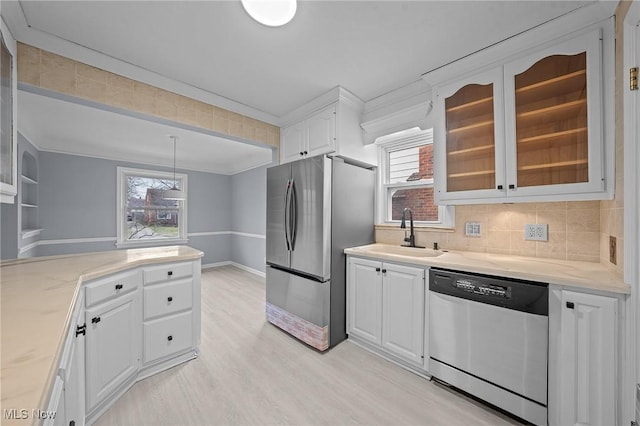 kitchen with stainless steel appliances, sink, white cabinets, light hardwood / wood-style floors, and hanging light fixtures