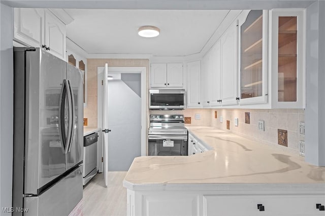 kitchen with white cabinets, light stone counters, stainless steel appliances, and tasteful backsplash