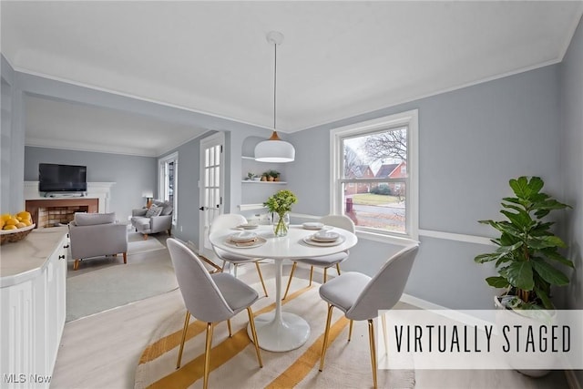 dining area with light wood-type flooring and ornamental molding