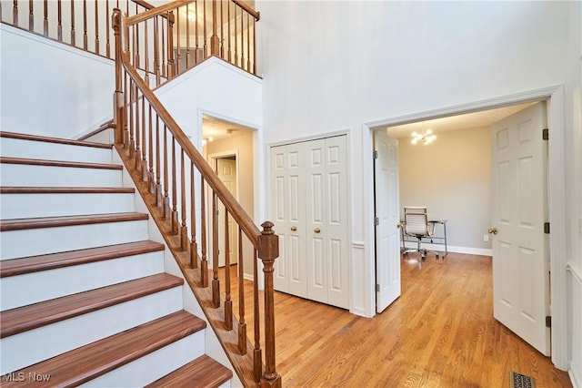 entrance foyer with light hardwood / wood-style flooring, a high ceiling, and an inviting chandelier