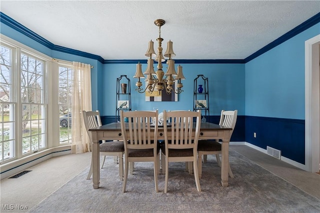 dining area featuring crown molding, a chandelier, a textured ceiling, and dark colored carpet