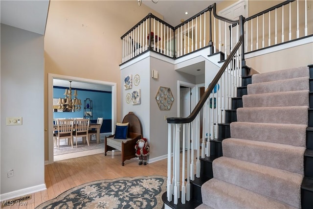 staircase featuring wood-type flooring and a high ceiling