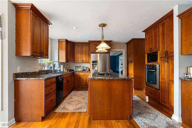 kitchen featuring sink, pendant lighting, a kitchen island, black appliances, and light wood-type flooring