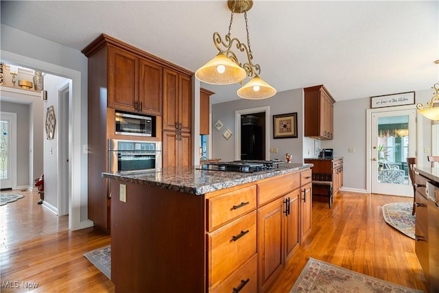 kitchen featuring built in microwave, stainless steel oven, a center island, hanging light fixtures, and black gas cooktop