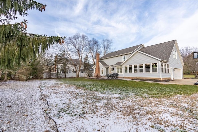 rear view of house with a garage and a lawn