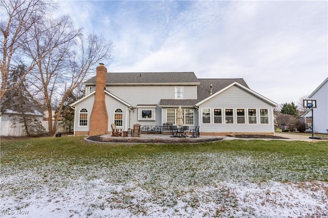 snow covered back of property featuring a lawn and a patio