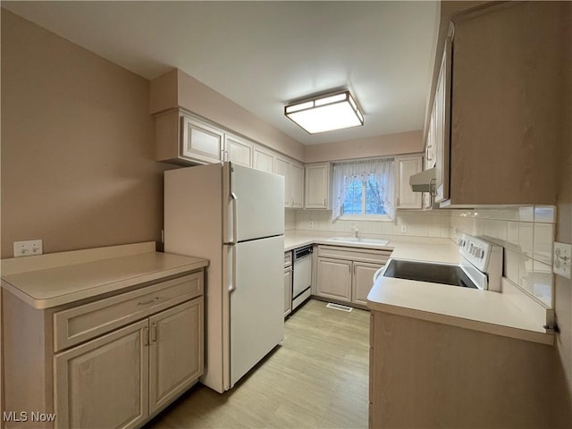 kitchen with decorative backsplash, white appliances, sink, and kitchen peninsula