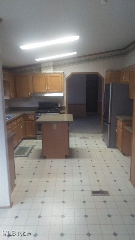 kitchen featuring a center island, stainless steel gas range oven, and black fridge