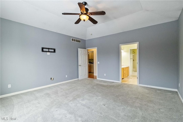 unfurnished bedroom featuring ensuite bath, ceiling fan, light colored carpet, and vaulted ceiling