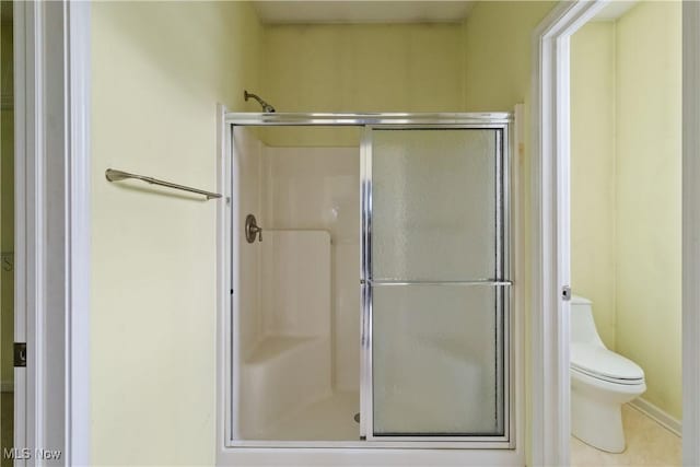 bathroom with tile patterned floors, toilet, and an enclosed shower