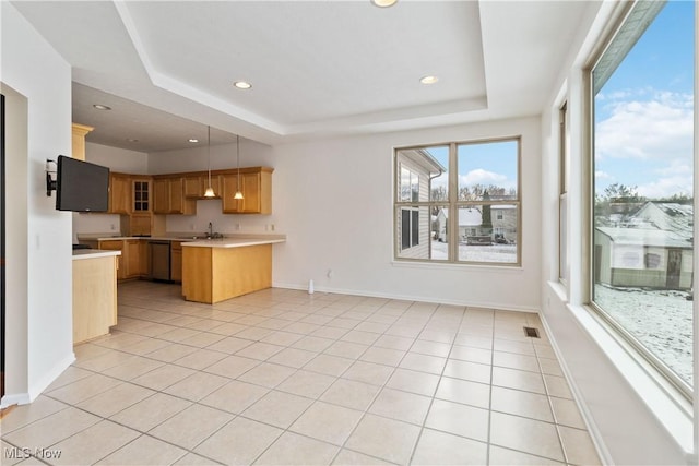 kitchen featuring kitchen peninsula, light tile patterned floors, a raised ceiling, and hanging light fixtures