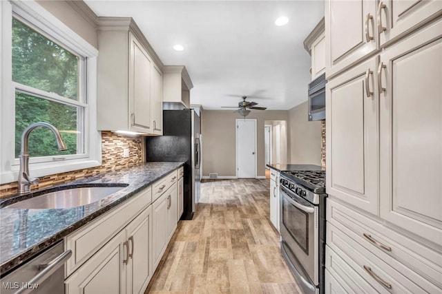 kitchen with sink, dark stone countertops, tasteful backsplash, white cabinetry, and stainless steel appliances