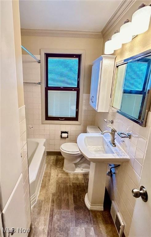 bathroom with sink, toilet, tile walls, and ornamental molding