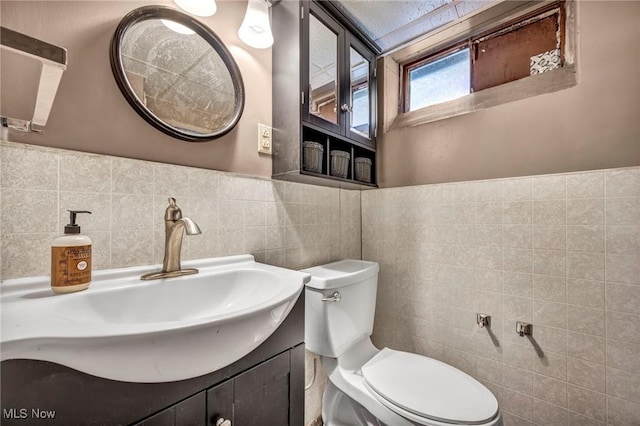 bathroom with vanity, toilet, and tile walls