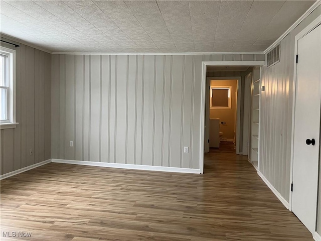 spare room featuring wood-type flooring and ornamental molding