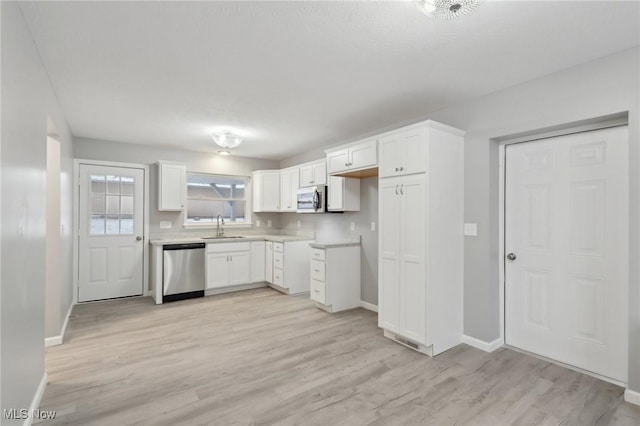 kitchen with white cabinets, light hardwood / wood-style floors, sink, and appliances with stainless steel finishes