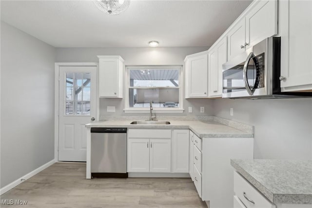 kitchen with light wood-type flooring, white cabinetry, sink, and appliances with stainless steel finishes