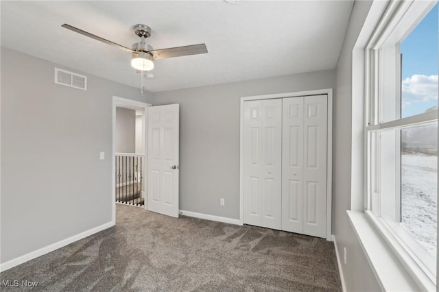 unfurnished bedroom featuring carpet flooring, multiple windows, ceiling fan, and a closet