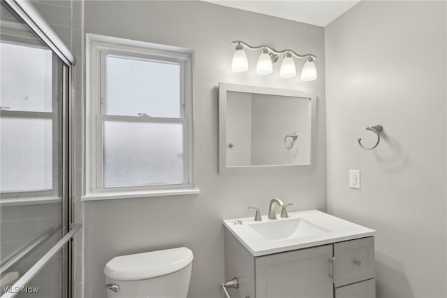 bathroom with a shower with door, vanity, and toilet