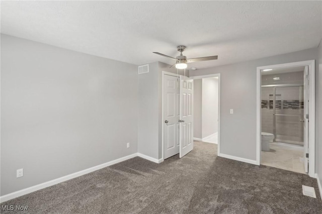 unfurnished bedroom featuring dark colored carpet, ceiling fan, and ensuite bath