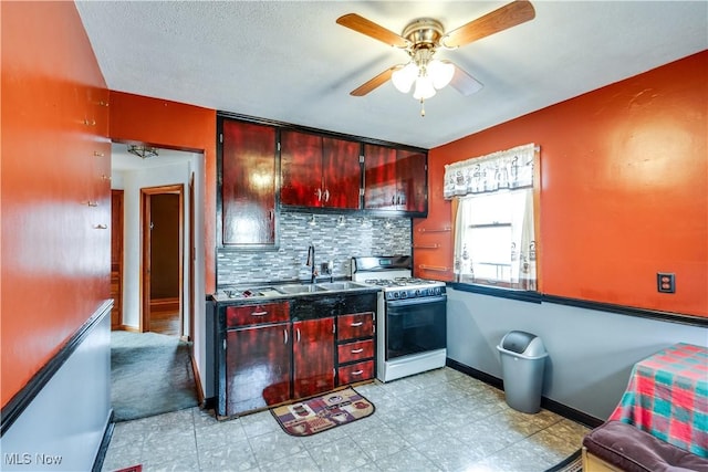 kitchen with backsplash, white gas range, ceiling fan, and sink