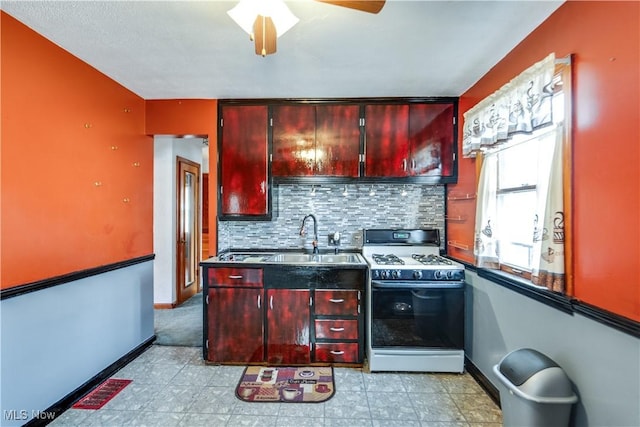 kitchen with decorative backsplash, white gas range oven, ceiling fan, and sink