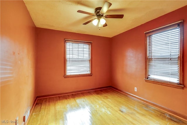 empty room with ceiling fan and light hardwood / wood-style floors