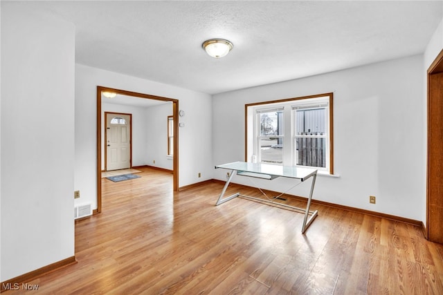 unfurnished dining area featuring light hardwood / wood-style floors and a textured ceiling