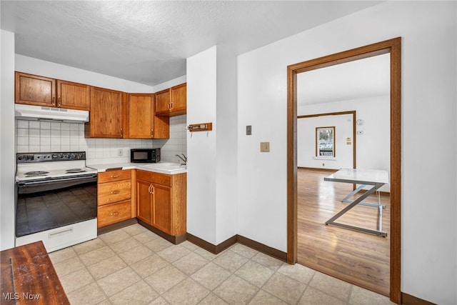 kitchen with a textured ceiling, electric range, tasteful backsplash, and sink