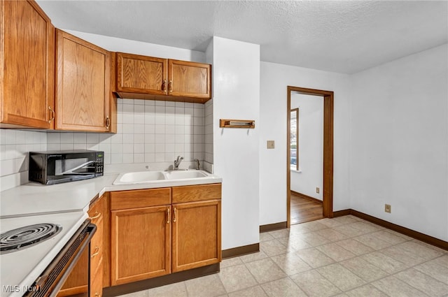 kitchen featuring a textured ceiling, backsplash, electric range, and sink