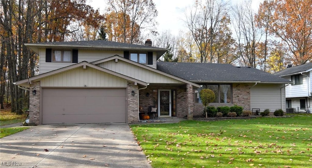 tri-level home with a front yard, central AC, and a garage