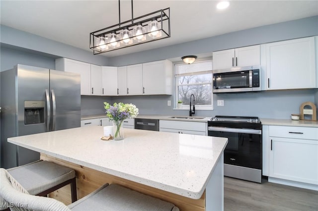 kitchen featuring white cabinetry, sink, pendant lighting, a kitchen island, and appliances with stainless steel finishes