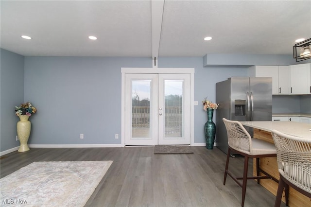 kitchen with french doors, hardwood / wood-style flooring, stainless steel fridge, beamed ceiling, and white cabinetry